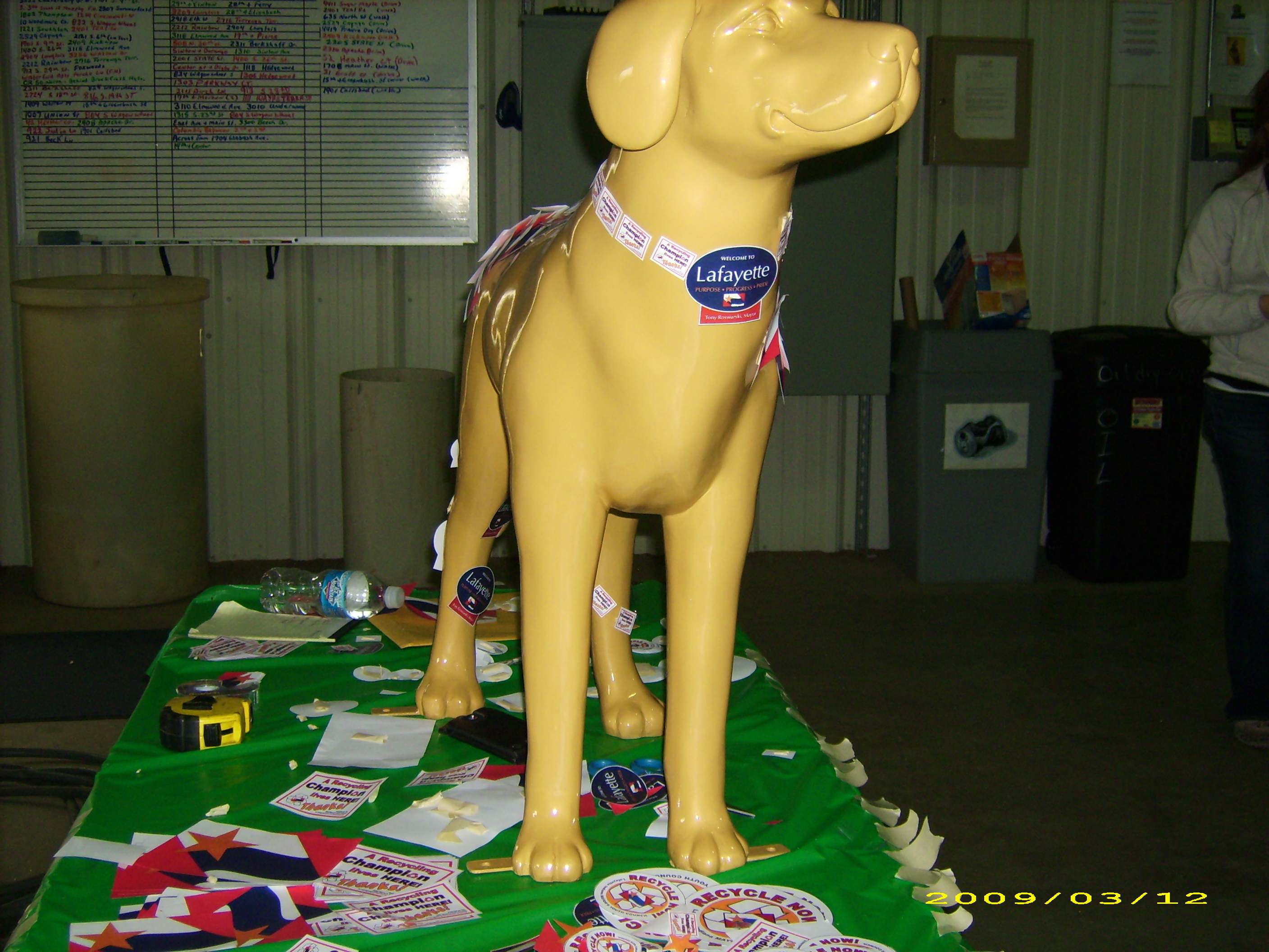 A plastic dog on a table with stickers on it